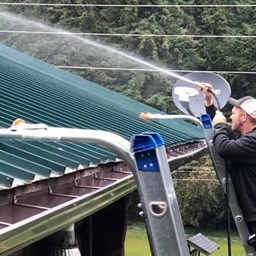 man pressure washing a roof